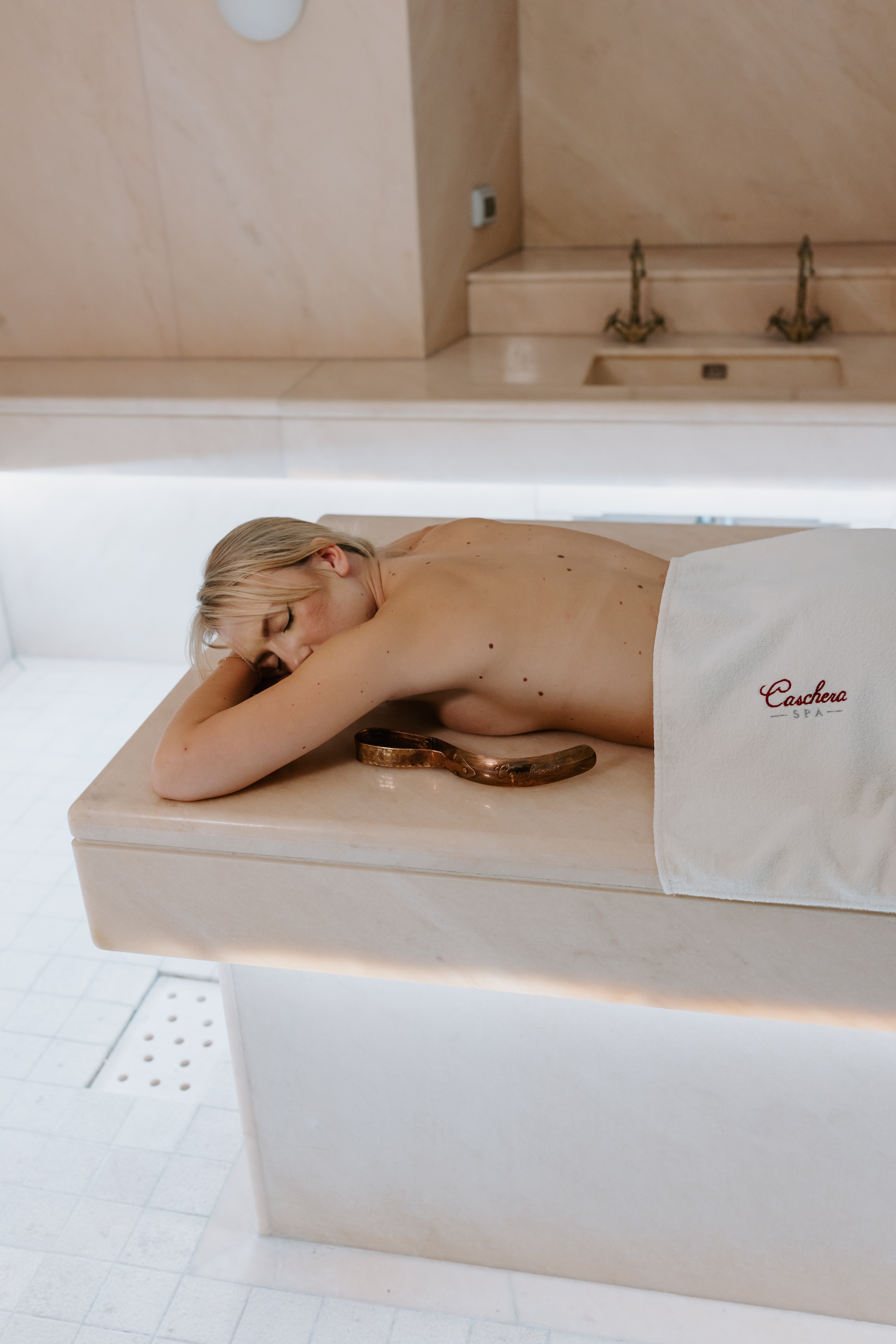 Woman lying on massage bed with hot stones on back