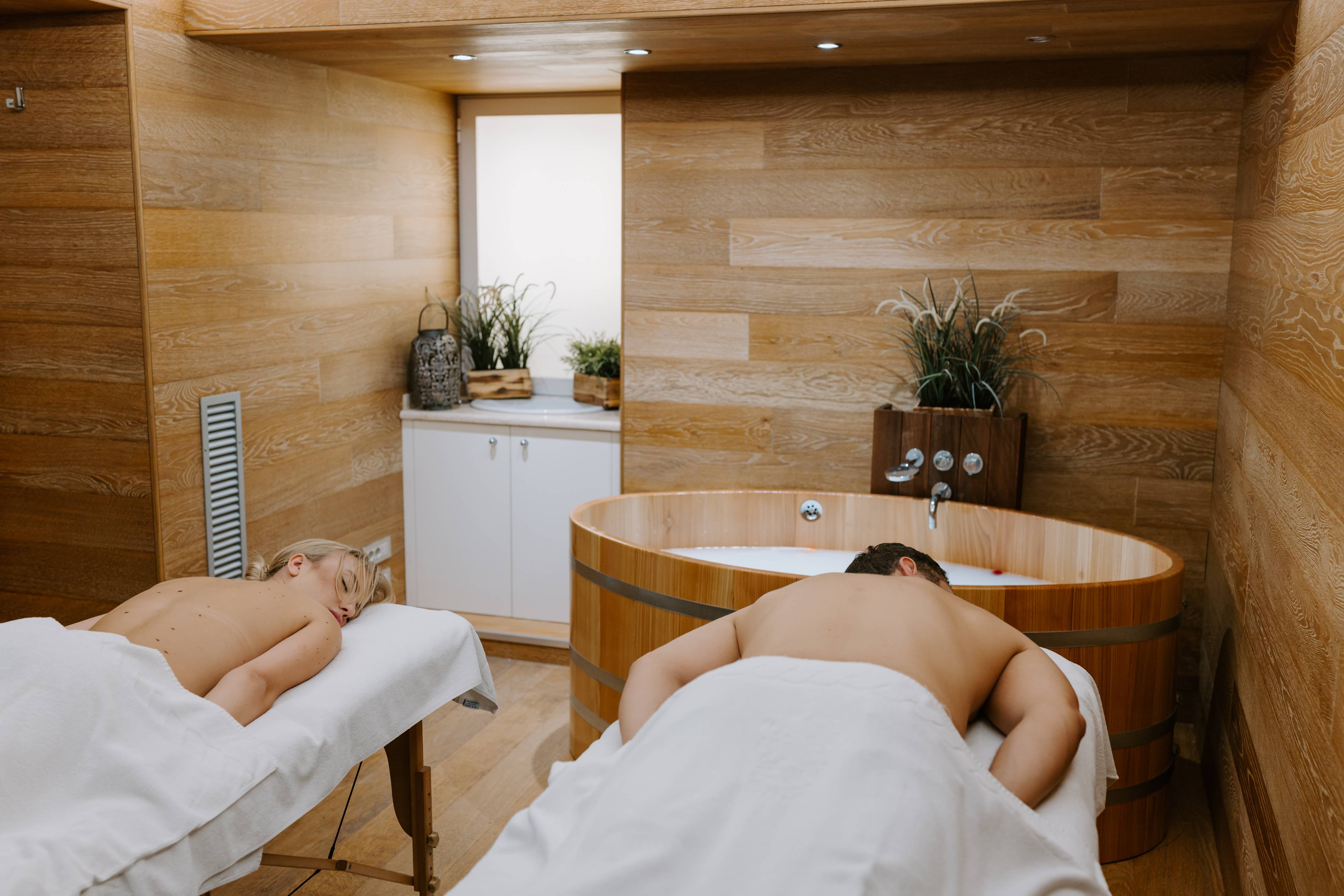 Couple relaxing in private room with wooden tub and massage beds